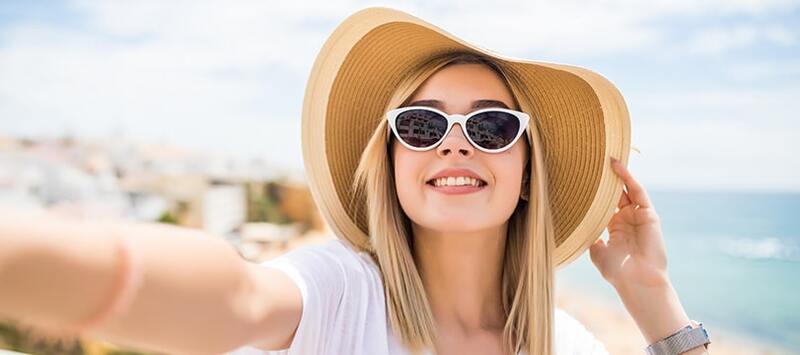 Beautiful girl wiith sunglasses taking selfie on beach